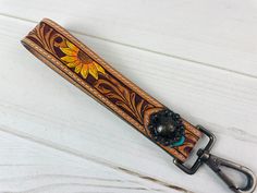 a brown leather key fobl with an orange flower on the front and yellow flowers on the back