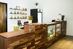 a wooden counter sitting inside of a room next to a wall filled with jars and plants