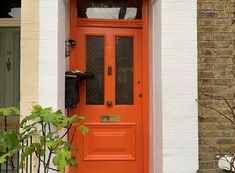 an orange front door on a white brick house