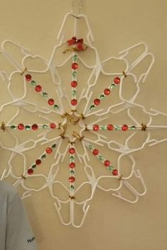 a white snowflake hanging on the wall with red and green beads attached to it