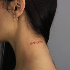 a woman's neck with the word annour tattooed on her left side ear