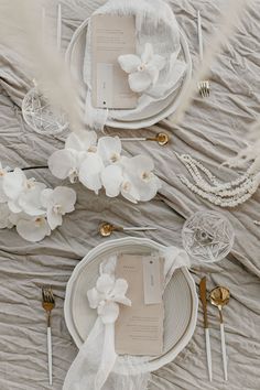 the table is set with white flowers and silverware