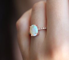 a woman's hand with a white opal and diamond ring on her finger