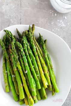 asparagus on a white plate with salt and pepper sprinkled on top