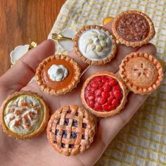 small miniature pies are sitting in the palm of someone's hand on a table