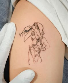 a woman's thigh with a tattoo design on the back of her leg, and a gloved hand holding it