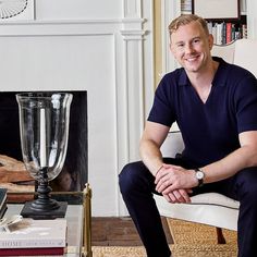 a man sitting on a chair in front of a fire place with a trophy next to him