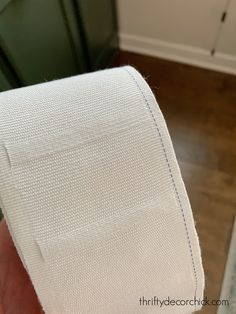 a roll of white toilet paper sitting on top of a wooden floor next to a green cabinet