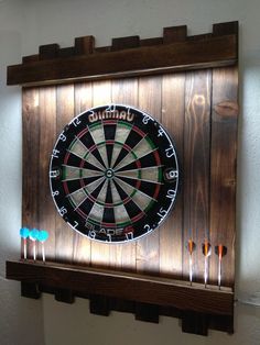 a dart board mounted to the side of a wall with darts in front of it