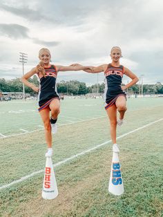 two cheerleaders are jumping on the field