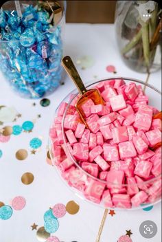 pink and blue candies in a glass bowl on a table with confetti