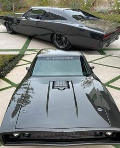 two black muscle cars side by side, one in grey and the other in black