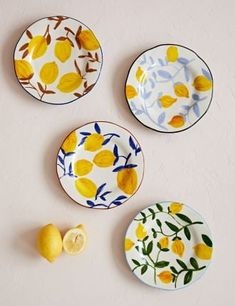 three plates with lemons and leaves painted on them next to a slice of lemon