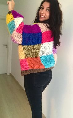 a woman is posing for the camera with her hand in her hair and wearing a multicolored sweater