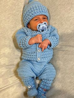 a baby wearing a blue crochet outfit with a pacifier in it's mouth