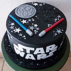 a star wars themed cake with two lightsabes on top and stars around it