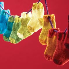 colorful socks hanging from a clothes line against a red background