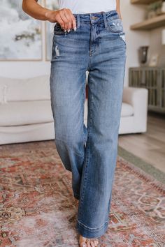 Experience effortless style with our Katrina High Waist Distressed Denim Trousers. Featuring a trouser-style hem, high rise waistline and wide leg cut with subtle distressing, these classic jeans in a medium wash will be your go-to pair of jeans. Get ready to be comfortable and look fabulous. Judy Blue High Rise Zip Fly Slight Distressing Medium Wash 92% Cotton, 6% Polyester, 2% Spandex True to Judy Blue Sizing 0/24: Waist 25" Hip 35" Rise 10.5" Inseam 32.5"1/25: Waist 26" Hip 36" Rise 10.5" Ins Hem Jeans, Judy Blue Jeans, Distressed Denim Jeans, Classic Jeans, Trouser Style, Ruffled Sleeve Top, Denim Trousers, Distressed Denim, Effortless Style