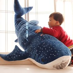 a little boy sitting on top of a stuffed whale