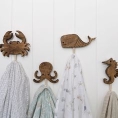 three wooden sea animals hanging from hooks on the wall next to towels and blankets in front of them