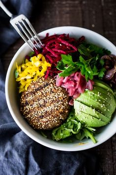 a white bowl filled with different types of vegetables and a burger on top of it