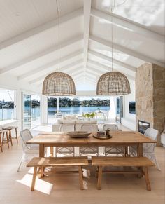 a dining room table with two chairs and a bench in front of a window that looks out onto the water