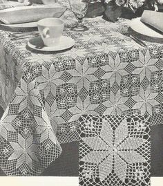 the table cloth is crocheted with white doily and has flowers on it