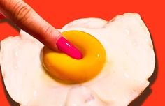 an egg being fried with a pink and yellow ring in it's center, on top of a red background