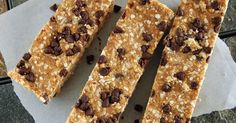 three pieces of granola bar sitting on top of a piece of parchment paper with chocolate chips