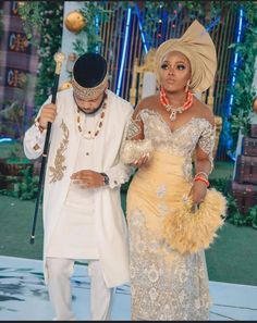 a man and woman dressed in traditional african garb standing next to each other on a stage