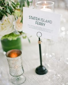 there is a sign that says state island ferry next to some wine glasses and flowers