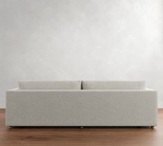 a couch sitting on top of a wooden floor next to a white wall and wood floors