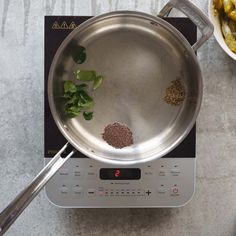 a frying pan on top of a stove with spices and herbs cooking in it