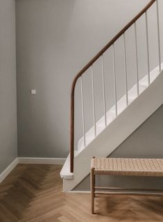 an empty room with a wooden bench and white railing on the wall next to stairs