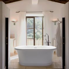 a large white bath tub sitting inside of a bathroom next to a doorway and window