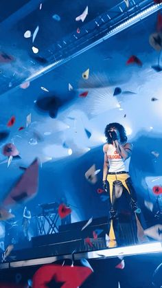 a woman standing on top of a stage next to microphones and confetti