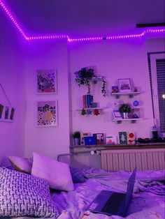 a laptop computer sitting on top of a bed in a room filled with purple lights