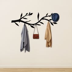 a coat rack with two coats hanging from it's hooks and a hat on the wall