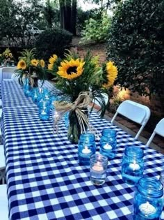 the table is set with blue glass jars and sunflowers