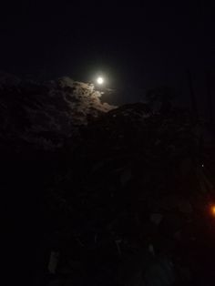 the full moon shines brightly in the night sky over a pile of rubble and debris