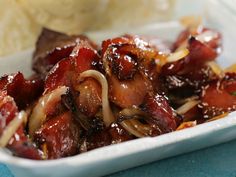 a close up of a plate of food with meat and onions in sauce on it