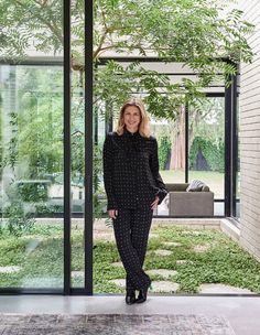 a woman standing in front of an open door with trees and grass on the ground