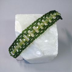 a green beaded bracelet sitting on top of a white rock