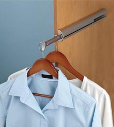 a light blue shirt hanging on a wooden hanger next to a white dress shirt