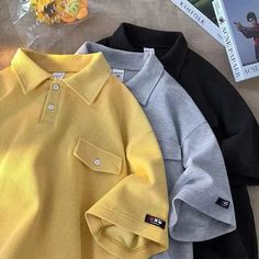 three polo shirts sitting on top of a bed next to a book and stuffed animal