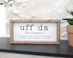 a potted plant sitting next to a sign that says uff da norwegian on it