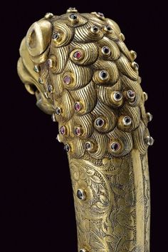 an ornate gold vase with lots of jewels on it's face and body, sitting against a black background