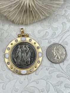 Three Graces Silver Coin Pendant Are you looking for a unique and meaningful accessory to add to your jewelry collection? Look no further than the Three Graces Coin Pendant! This beautifully crafted pendant features a silver coin depicting the three daughters of Zeus, each representing a special gift to humanity. From left to right: Euphrosyne (mirth), Aglaia (elegance) and Thalia (youth and beauty). Made of high-quality zinc alloy, brass, mother of pearl, and cubic zirconia, this pendant is not Commemorative Brass Pendant Jewelry, Collectible Metal Jewelry With Coin Pendant, Victorian Style Oxidized Gold Jewelry, Antique Coin-shaped Metal Jewelry, Antique Coin Shaped Metal Jewelry, Victorian Round Pendant Jewelry For Commemoration, Antique Finish Gold Jewelry For Commemoration, Gold Antique Finish Jewelry For Commemoration, Antique Finish Round Jewelry For Anniversary