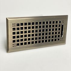 a metal grate with holes in it on a white surface