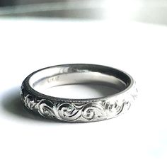 a wedding band with an intricate design on the inside and outside, sitting on a white surface